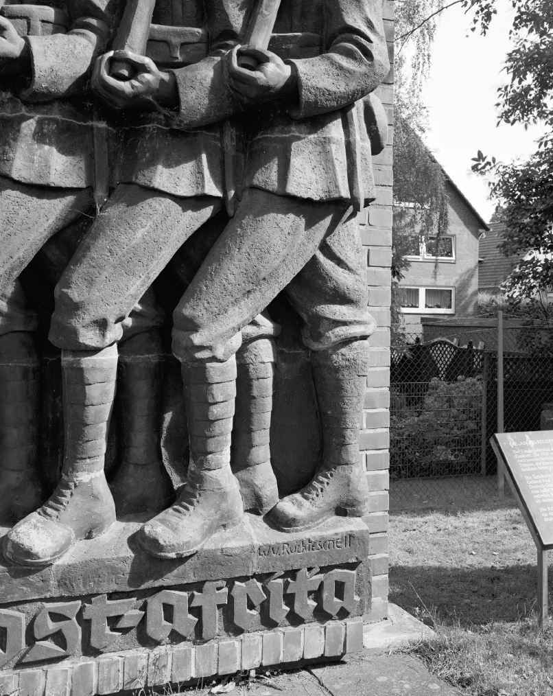 Zweiteiliges Kriegerdenkmal zur Ehrung der Schutztruppen in der Kolonie Deutsch-Ostafrika, ursprünglich rechts und links des Eingangs der Lettow-Vorbeck-Kaserne in Hamburg-Jenfeld, eingeweiht 13. August 1939. Dargestellt sind afrikanische Lastenträger und ein Askari-Soldat auf der linken Seite und Askari und ein deutscher Offizier auf der rechten Seite. In den Kämpfen gegen die alliierten Truppen kamen zwischen 1914 und 1918 etwa eine halbe Million Menschen, vorwiegend afrikanische Zivilisten, durch Kriegseinwirkungen ums Leben. Beide Denkmäler entstanden nach Entwürfen von Walter von Ruckteschell (1882-1941).