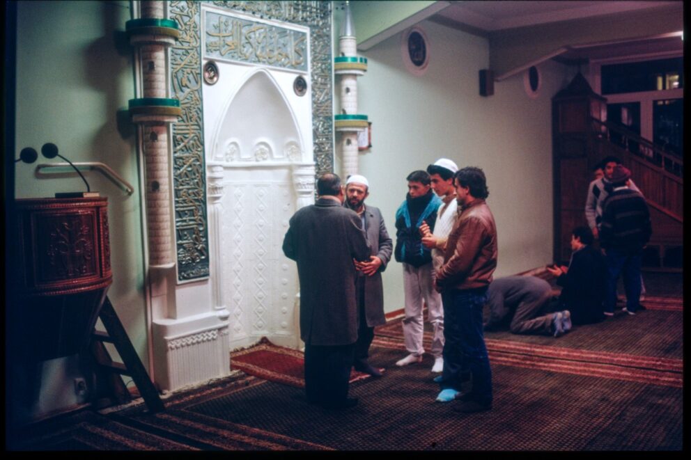 Imam Abdourahmane Disma im Gespräch mit Gläubigen vor dem Mihrab des Männergebetsaales der Ravzah-Moschee in der Böckmannstraße, Hamburg-St. Georg